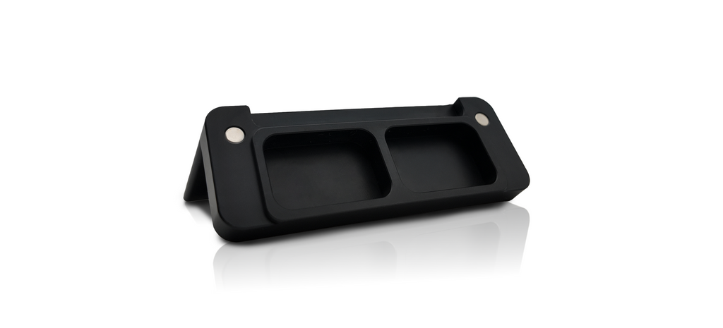The bottom of a black plastic slot cover showing two inset magnets on a white background.