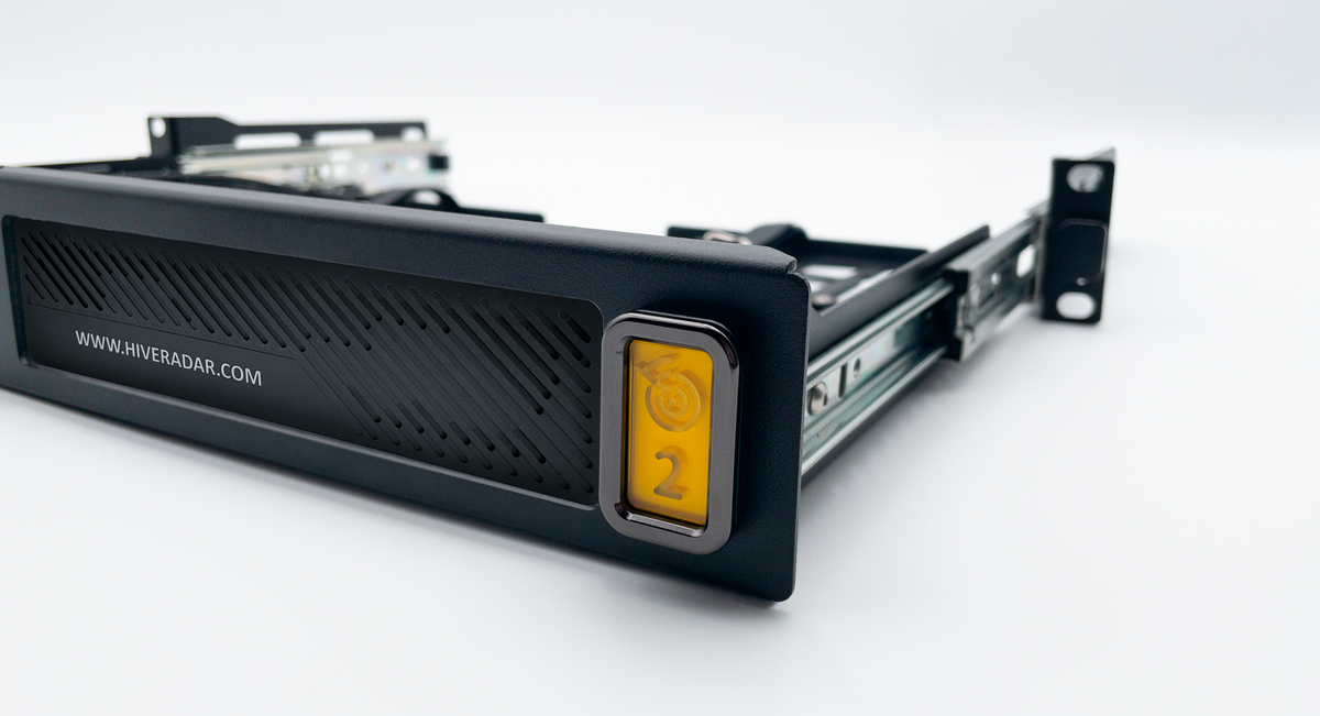 A close-up of a black metal server rack frame with yellow accent LED lights and a slot cover fitted into a unit cradle, photographed on a clean white studio background.